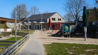 Außengelände des Ev. Kindergartens Husby mit Spielgeräten, Sandfläche und dem Zugang zum Haupteingang